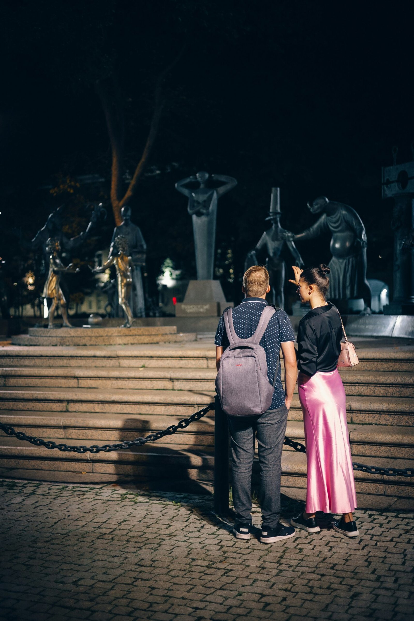 A man and a woman standing in front of a statue